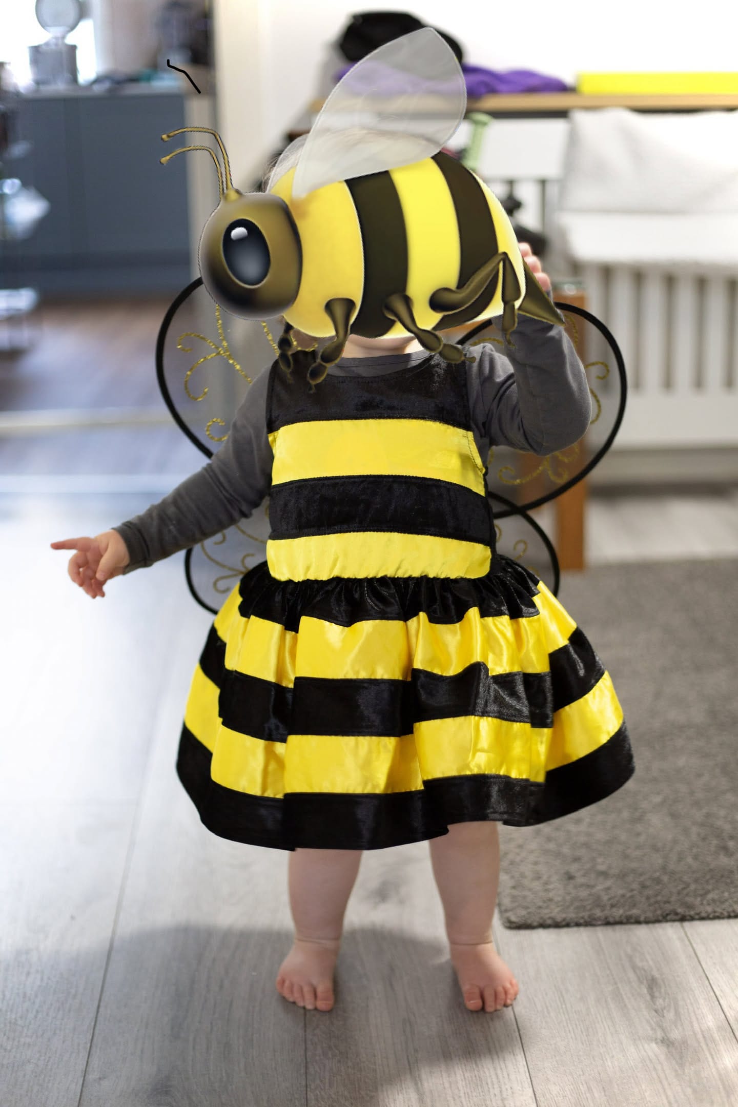 A photograph of a girl nearly 2 years old dressed in a bee costume.